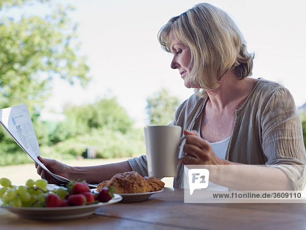 Woman outdoors with breakfast and newspaper