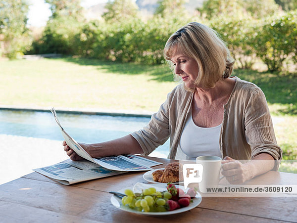 Woman outdoors with breakfast and newspaper