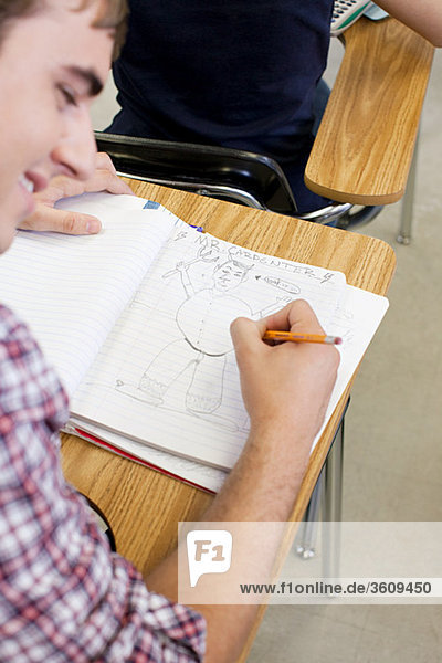 Male high school student doodling in notebook