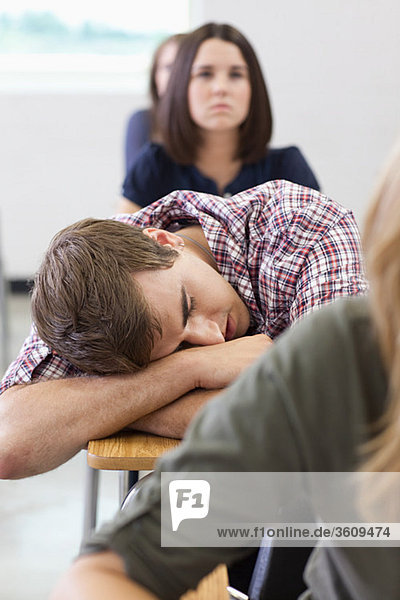 Männlicher Gymnasiast schläft in der Klasse