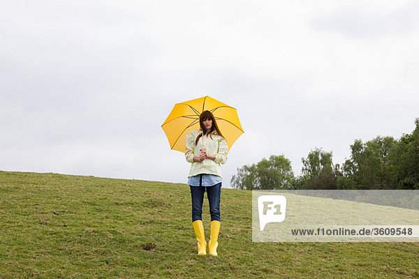 Junge Frau im Feld mit Regenschirm