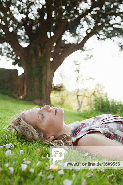 Junge Frau auf Gras liegend mit geschlossenen Augen