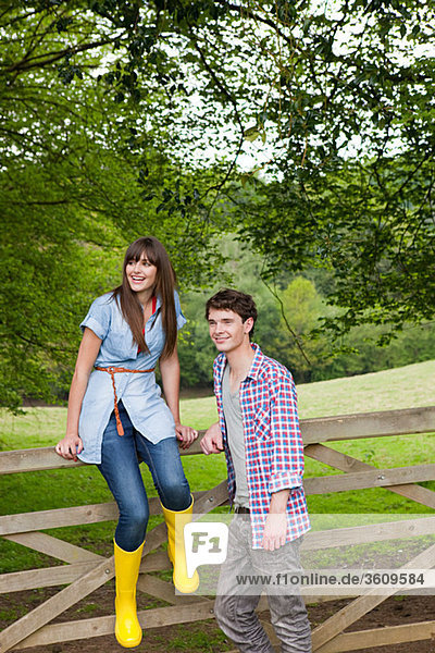 Young couple by gate in countryside