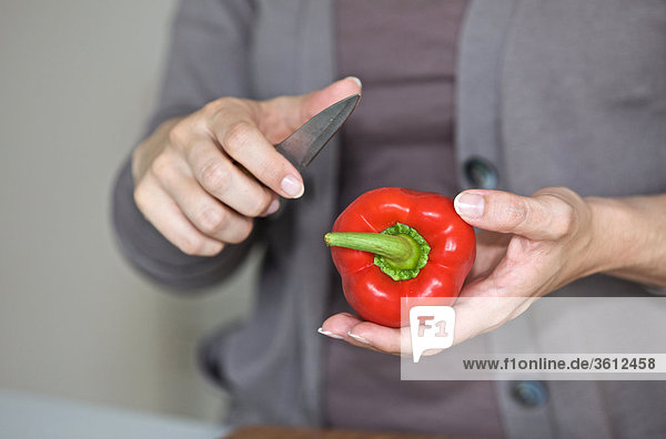 Woman slicing pepper in kitchen  close-up
