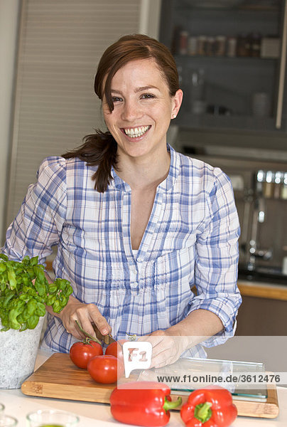 Frau schneidet Tomaten in der Küche
