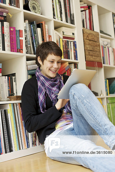 Junge Frau benutzt einen iPad vor einem Bücherregal