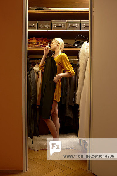 Junge Frau sucht sich ein Kleid aus dem Kleiderschrank aus