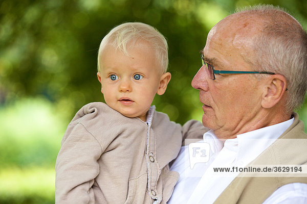 Großvater trägt Kleinkind im Freien  Portrait