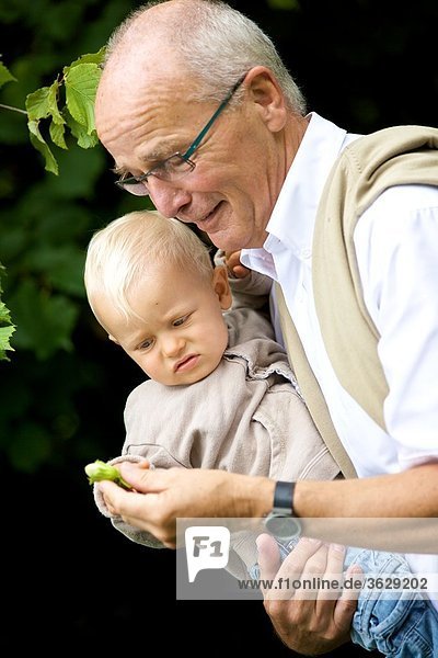 Großvater trägt Kleinkind im Freien