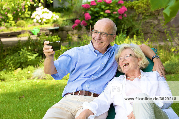 Happy senior couple with smartphone in garden