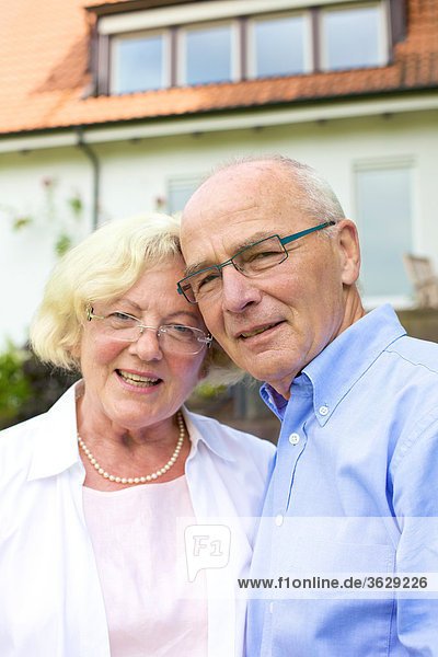 Happy senior couple in front of residential building  portrait