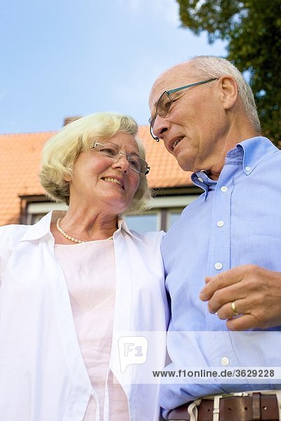 Glückliches Seniorenpaar vor Wohnhaus