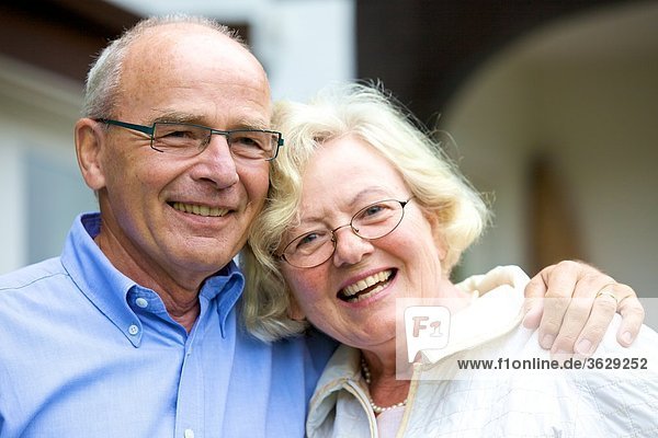 Glückliches Seniorenpaar umarmt sich vor Wohnhaus  Portrait