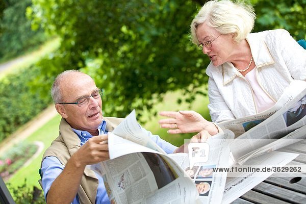 Seniorenpaar liest Zeitung auf der Terrasse