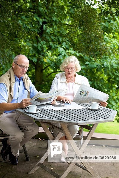 Seniorenpaar liest Zeitung auf der Terrasse