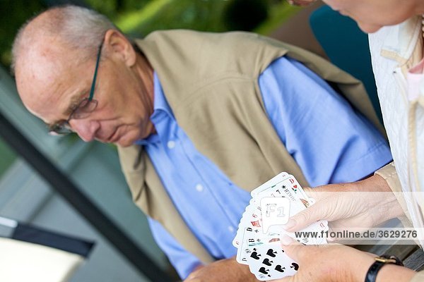 Seniorenpaar spielt Karten auf der Terrasse