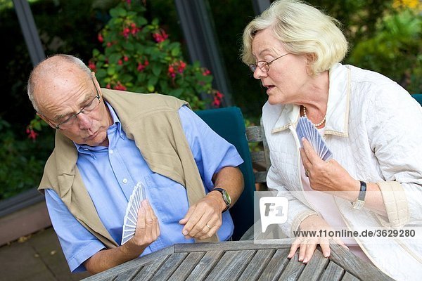 Seniorenpaar spielt Karten auf der Terrasse