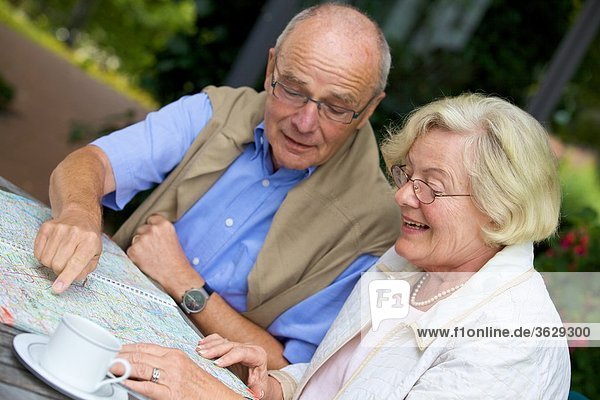 Seniorenpaar auf der Terrasse schaut auf Straßenkarte