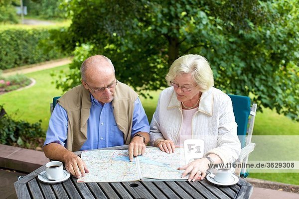 Seniorenpaar auf der Terrasse schaut auf Straßenkarte