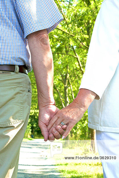 Seniorenpaar geht Hand in Hand spazieren