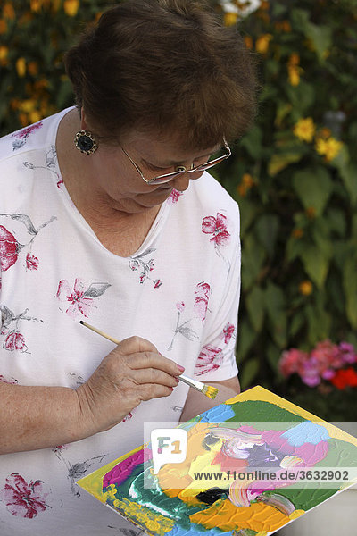 74jährige Frau beim Malen mit Acrylfarben