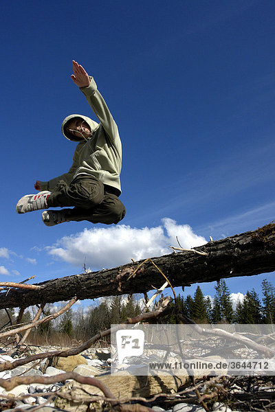 Junge springt über Baumstamm
