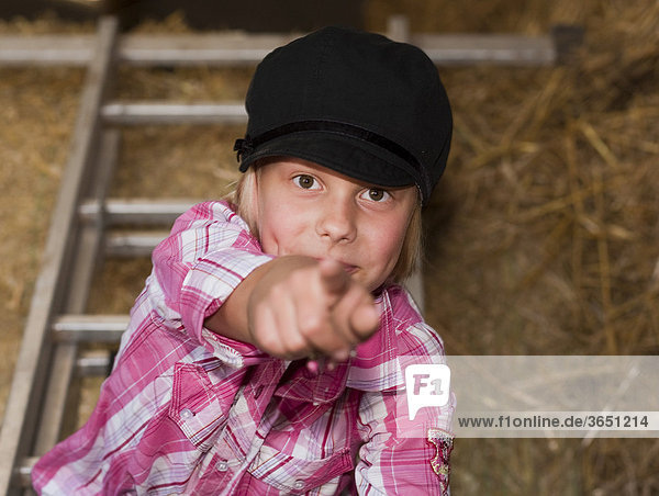 8-jähriges Mädchen steht auf einer Leiter und zeigt mit dem Finger nach vorn