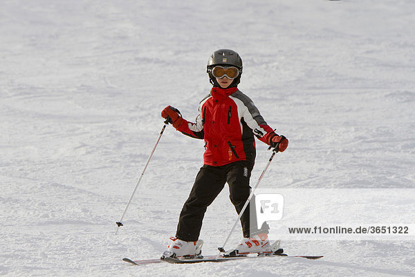 Girl  9  with a helmet  learning the snowplough on a pair of skis