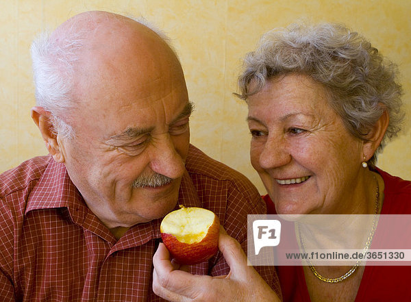 Frau füttert Mann mit Apfel  Rentnerpaar