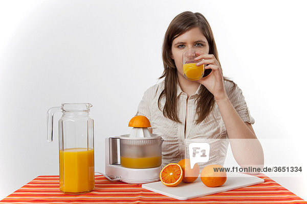 Junge Frau trinkt frisch gepressten Orangensaft