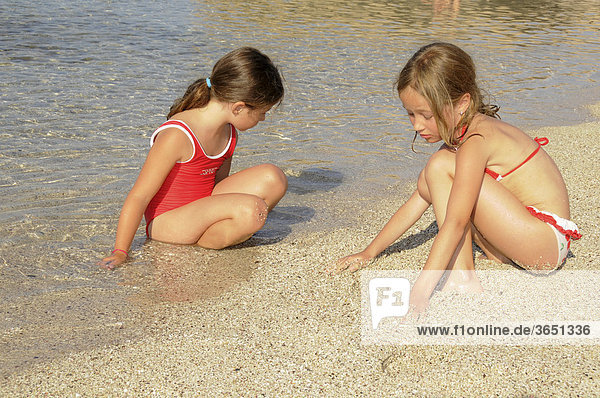 Zwei Mädchen spielen am Sandstrand