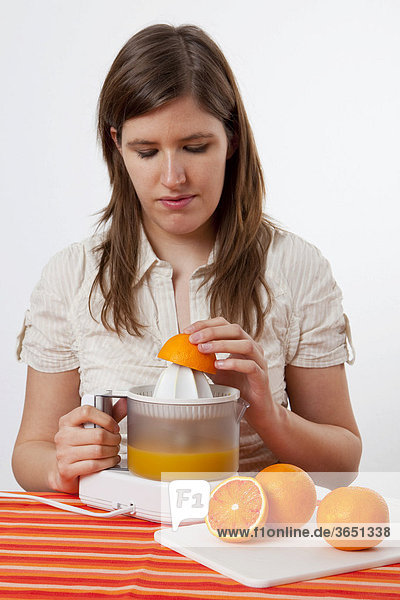 Junge Frau presst frischen Orangensaft