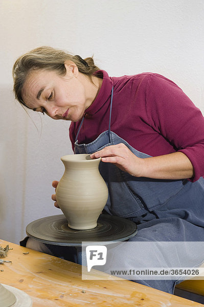 Keramikerin arbeitet in ihrer Werkstatt auf der Drehscheibe  poliert Oberfläche eines Krugs  Geisenhausen  Bayern  Deutschland  Europa