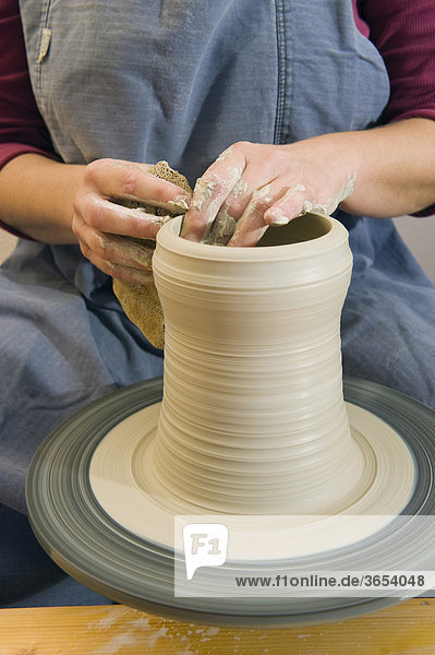 Keramikerin arbeitet in ihrer Werkstatt auf der Töpferscheibe  Zylinder hochziehen  Geisenhausen  Bayern  Deutschland  Europa
