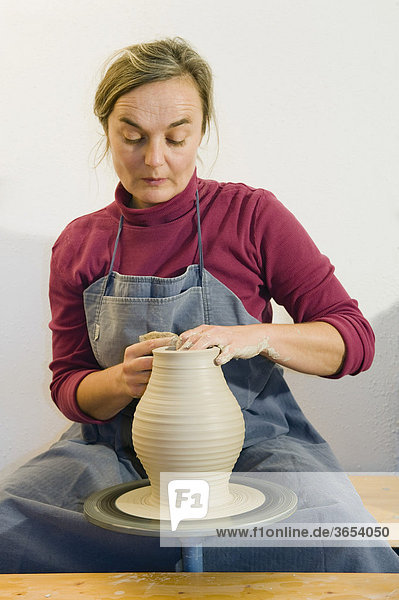Keramikerin arbeitet in ihrer Werkstatt auf der Töpferscheibe  Drehen einer Vase  Geisenhausen  Bayern  Deutschland  Europa