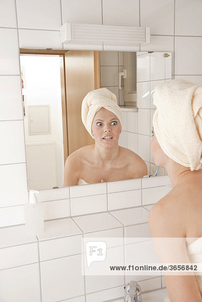 Junge Frau mit Handtuch auf dem Kopf vor dem Spiegel