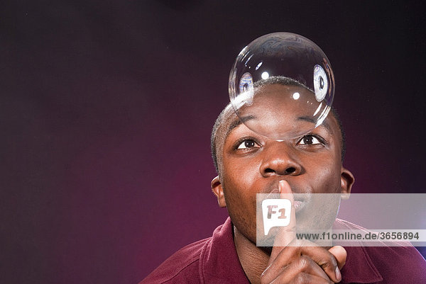 Dark-skinned young man with soap-bubble  making a gesture of silence
