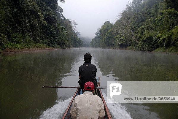 Solitary wooden boat floating upstream on the Nam Ou River  mist and jungle on the river bank  Ban Sopkang  Phou Den Din National Protected Area  Phongsali or Phongsaly District and Province  Laos  Southeast Asia  Asia