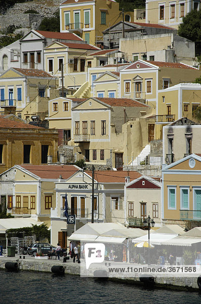 Blick auf die farbenfrohen ockerfarbenen Häuser über der Promenade der Insel Symi Griechenland
