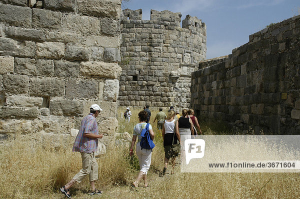 Antikes Griechenland aktive Senioren Frau wandert mit einer Gruppe durch das trockene Gras zwischen hohen Mauern der Festung der Johanniter Insel Kos Griechenland