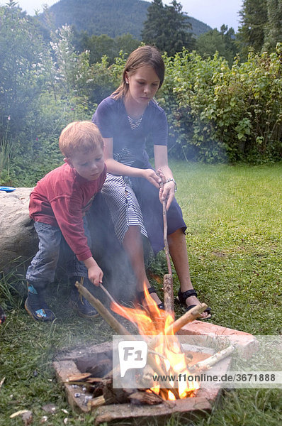 Kinder beim Grillen am Lagerfeuer Spiel mit dem Feuer