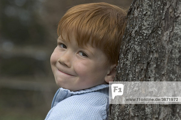 Kleiner Junge vier Jahre lehnt an einem Baum
