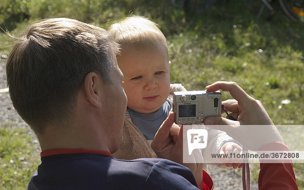 Father is taking pictrures of his little son