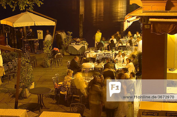 Orta Piedmont Piemonte Italy people are celebrating and eating in a Restaurant at the lake by twighlight