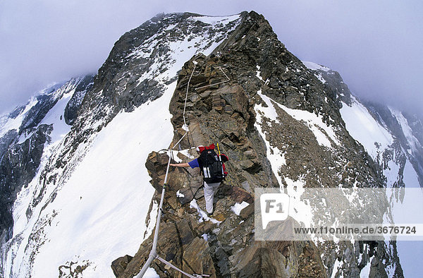 Bergsteigerin klettert auf einem Grat zum Rifugio Quintino Sella Wallis Italien