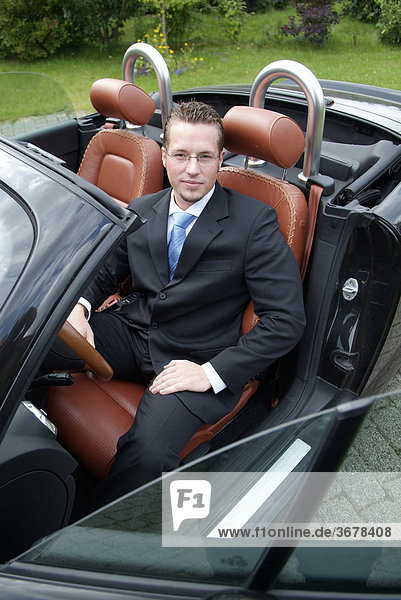 Man in the suit sits in his sports car