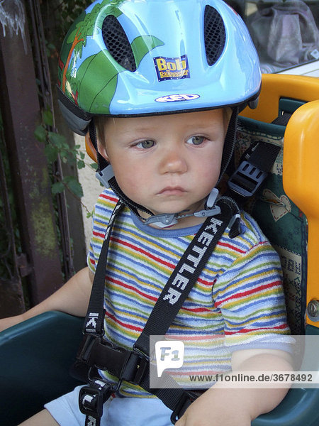 Child with helmet in bicycle child seat