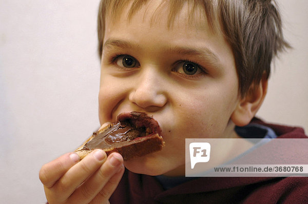 Junge ißt brot mit nougatcreme