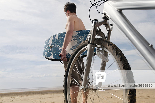 Mann am Strand mit Fahrrad und Boogieboard