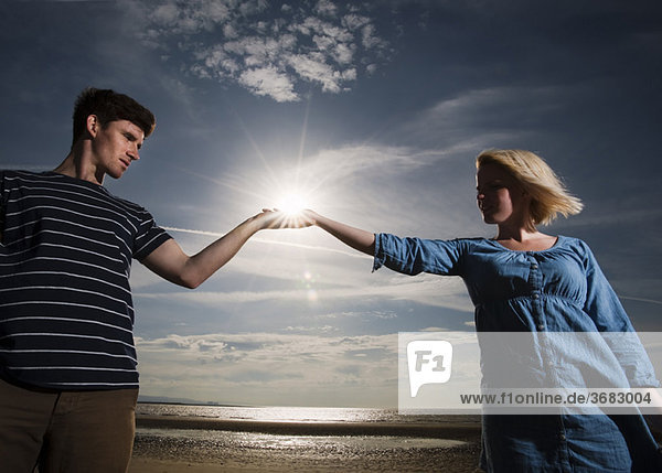 Paar am Strand hält Sonne in Händen